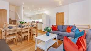 Una sala moderna con un sofá gris, una mesa de comedor de madera y sillas.