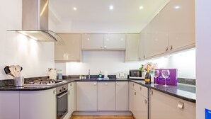 Una cocina moderna con armarios blancos, una campana extractora de acero inoxidable y un microondas.
