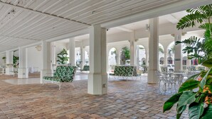 Une cour intérieure avec un sol en briques, des colonnes blanches et des plantes vertes.