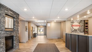 Un hall d’hôtel avec une cheminée en pierre, un comptoir d’accueil et un panneau indiquant les en-cas disponibles.