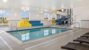 Une piscine intérieure avec un toboggan, des chaises longues et un espace détente aux couleurs bleu et jaune.