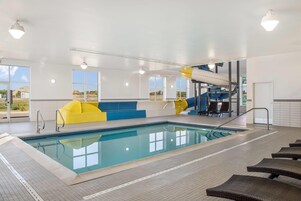 Una piscina techada, sillones reclinables de piscina