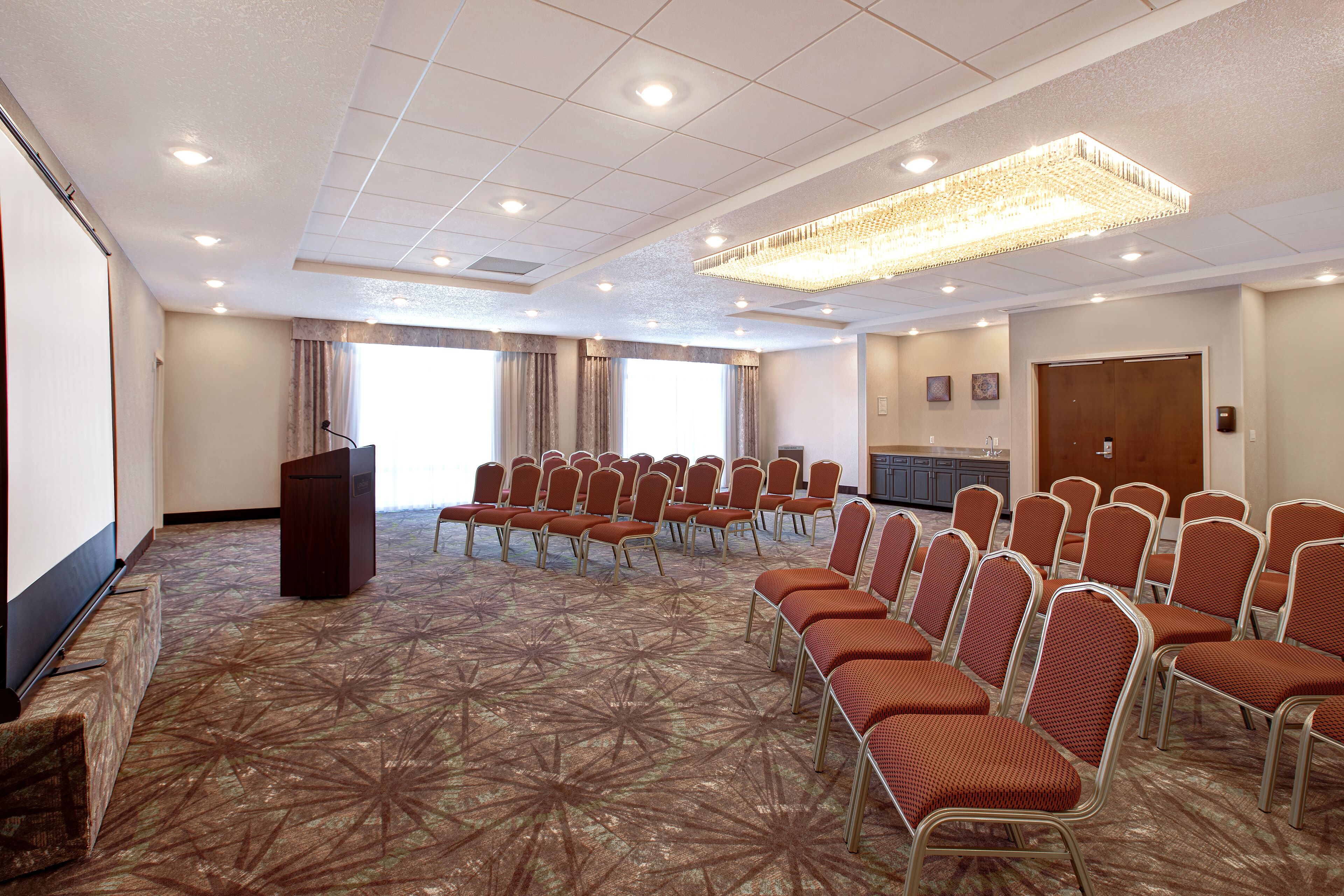 A conference room with rows of chairs, a podium, and a large chandelier.