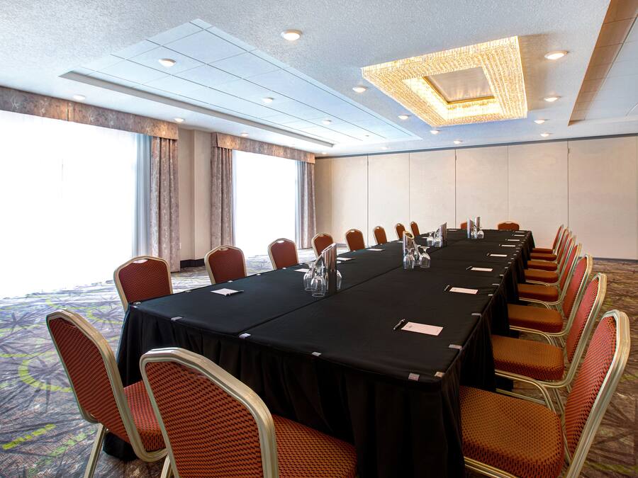 Een vergaderzaal met een lange tafel, stoelen en een kroonluchter.