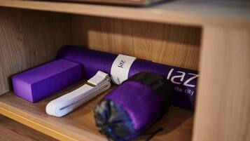A wooden shelf with a purple yoga mat, a rolled-up towel, and a black bag with a white label.