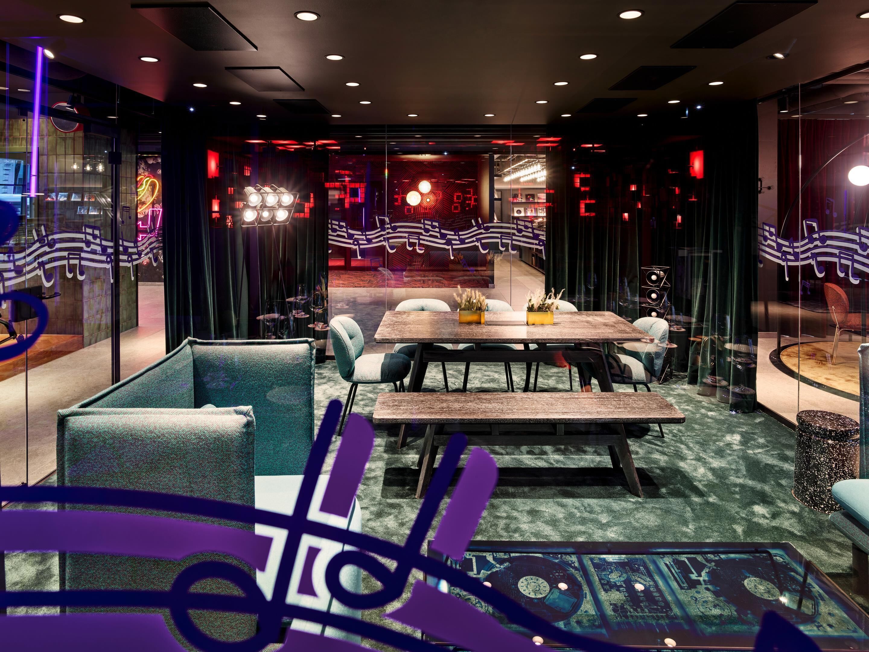 A modern interior with a central dining table, seating, and a glass partition with a view.