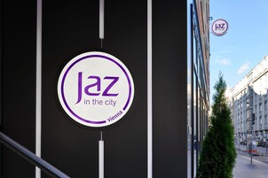 Placa com a inscrição 'Jaz na cidade Viena' numa fachada de prédio.