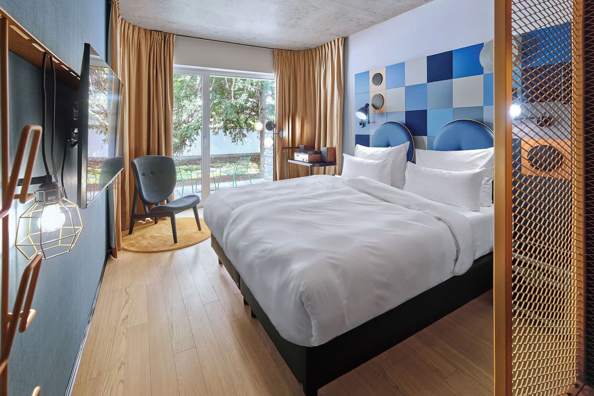 Une chambre d’hôtel avec un lit, une chaise, un bureau et une vue sur l’extérieur.