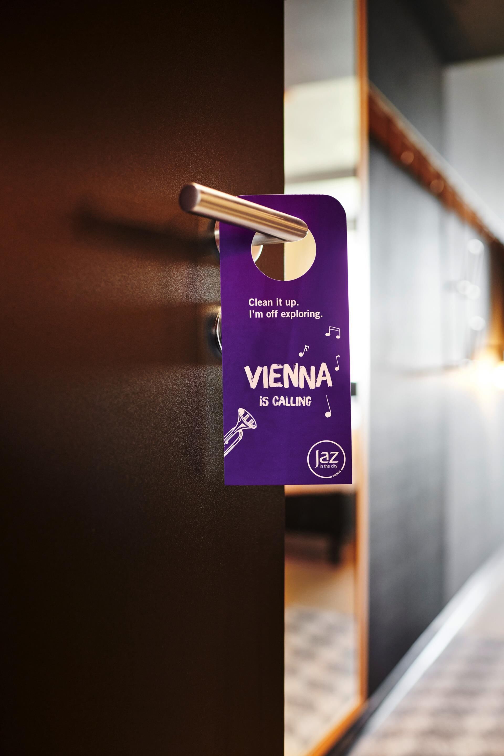 Une enseigne violette sur une porte, avec le texte « VIENNE VOUS APPELLE » et un logo.
