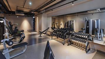 A gym with various exercise equipment, including treadmills, weight machines, and a rack of dumbbells.
