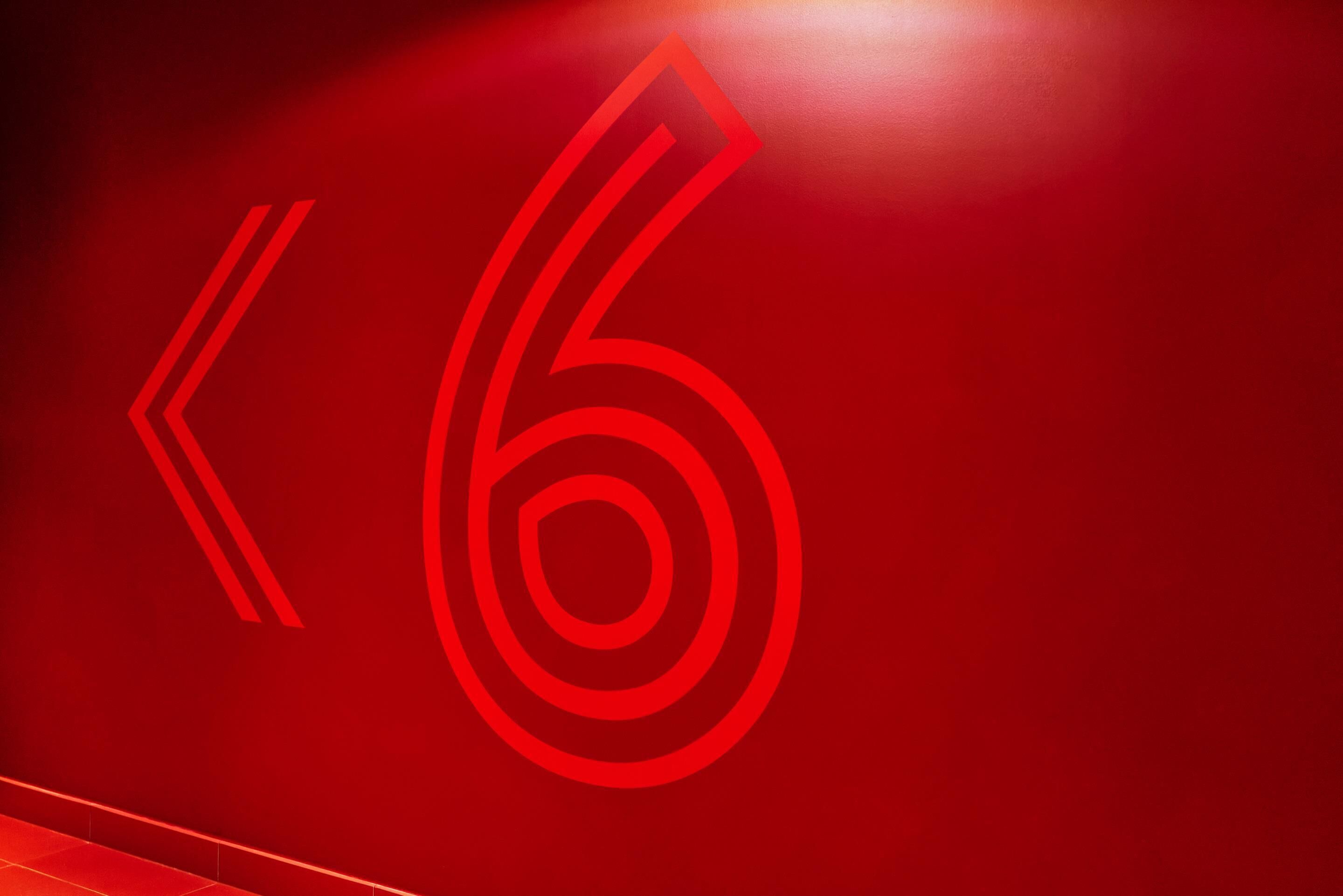 Una pared roja con el número '6' estilizado.