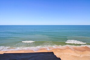 A beach with clear blue water and a sandy shore. - Direct Oceanfront Views from Luxury Condo in Southwind Complex! (New Smyrna Beach)