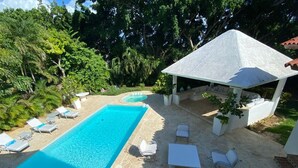 A swimming pool with lounge chairs and a gazebo in a garden setting. - Lux Villa, Casa de Campo (La Romana)