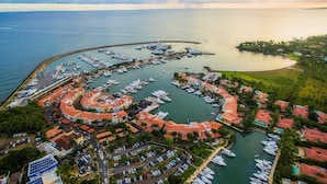 An aerial view of a marina with boats docked in a circular pattern, surrounded by residential buildings with red-tiled roofs. - Lux Villa, Casa de Campo (La Romana)