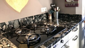 Una cucina con piano cottura nero, un ripiano in granito e una luce a forma di cuore sulla parete.