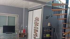 Un saló amb un sofà, una televisió, una paret amb indicadors de direcció, una escala i una finestra.