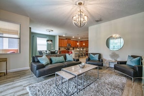 A modern living room with a sectional sofa, a coffee table, and a chandelier.