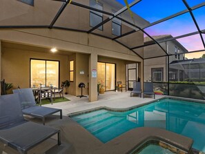 An indoor swimming pool with lounge chairs and a covered patio area.
