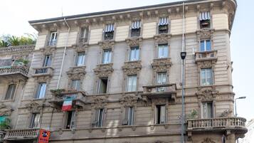 A multi-story building with classical architecture, featuring ornate balconies and a flag.