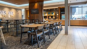 Un restaurant doté de plusieurs tables et chaises, d’un écran de télévision et d’un espace cuisine où divers articles sont exposés.