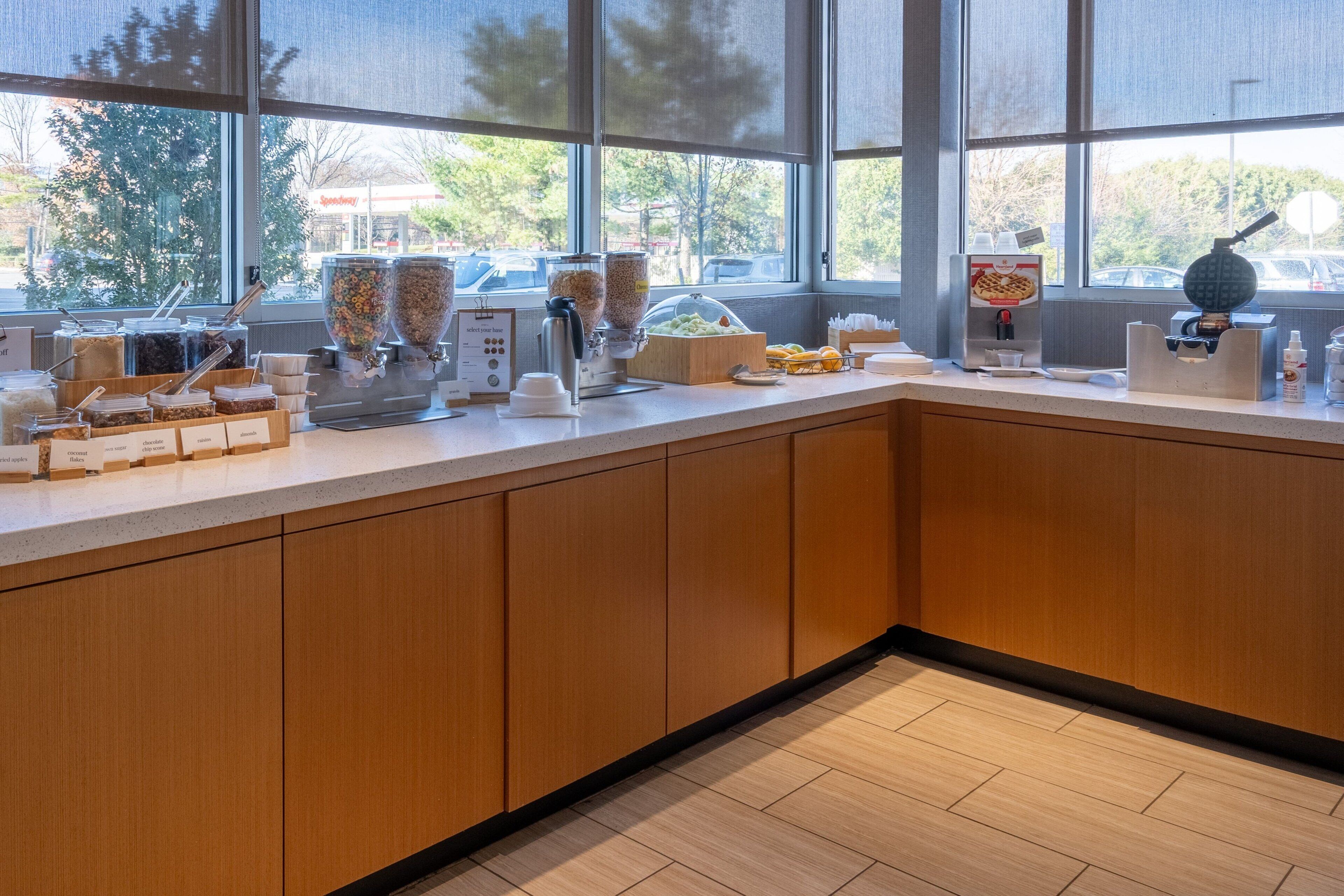 A modern kitchen with a large window, wooden cabinets, and various food dispensers.