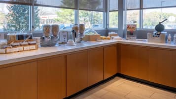 A modern kitchen with a large window, wooden cabinets, and various food dispensers.