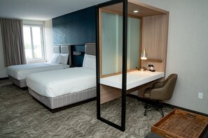 Une chambre d’hôtel avec deux lits, un bureau, une chaise et un petit plateau en bois.