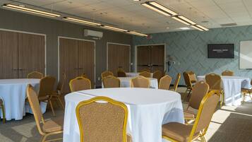 A conference room with round tables and chairs, a whiteboard, and an exit sign.