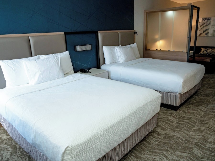 Habitación de hotel con dos camas, una mesita de noche, un teléfono y un espejo.