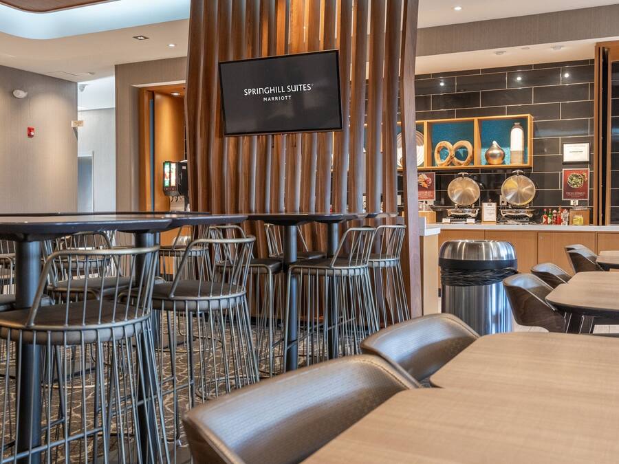 Rebedor d'hotel amb zona de bar, espais d'estada i una pantalla de televisió que mostra 'SPRINGHILL SUITES MARRIOTT'.