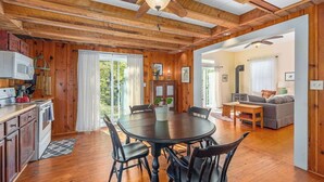 Interior de madera con una mesa de comedor, sillas, una zona de cocina y una sala de estar con un sofá.