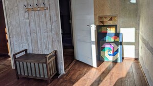 Ein Zimmer mit einer hölzernen Bank, einer weißen Tür und einem farbenfrohen Wandbild mit geometrischen Formen.