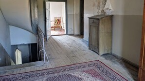 Ein Flur mit Holzboden, einem gemusterten Teppich, einem Holzstuhl und einem Schrank.