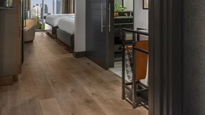 A modern hotel room with a large bed, a desk, and a view of the city skyline. - The Tess, Autograph Collection (Atlanta)