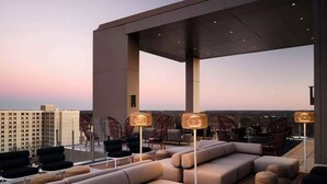 A rooftop lounge with modern seating and floor lamps, overlooking a cityscape at dusk. - The Tess, Autograph Collection (Atlanta)