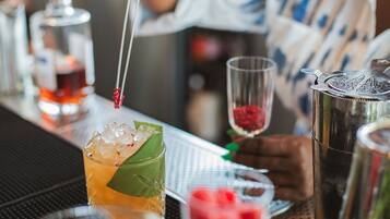 Un bar con una variedad de bebidas, incluyendo un cóctel con decoración, un vaso con adorno rojo y una botella de licor.