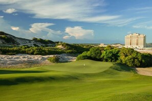 A golf course with a building in the background. - InterContinental Grand Ho Tram (Ho Chi Minh City)