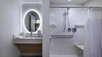 Een moderne badkamer met een wastafel, spiegel, douche en toilet.