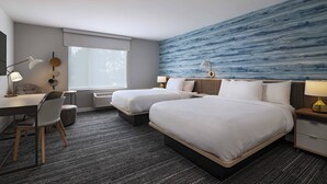 Une chambre d’hôtel avec deux lits, un bureau, une chaise, une lampe et une grande fenêtre.