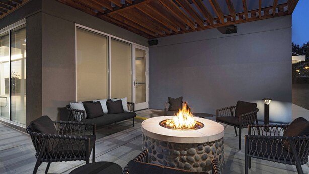 Une terrasse extérieure dotée d’un foyer en pierre, de meubles en osier et d’une pergola en bois.