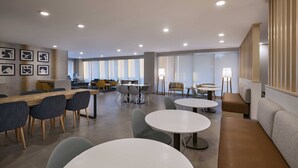 Un espace repas moderne avec des tables rondes, des chaises et une longue table en bois.