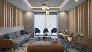 Un espace de détente moderne comprenant un canapé, des fauteuils, une table basse et une petite table à manger avec des chaises.