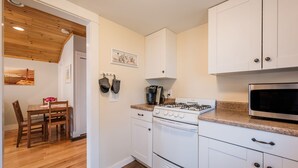A compact kitchen with white cabinets, a gas stove, a microwave, and a coffee maker. - Relaxing Getaway with Town Beach Access (Westerly)