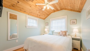A bedroom with a wooden ceiling, a large bed, two bedside tables, and a ceiling fan. - Relaxing Getaway with Town Beach Access (Westerly)