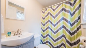 A bathroom with a white sink, a toilet, and a shower curtain with a zigzag pattern. - Relaxing Getaway with Town Beach Access (Westerly)