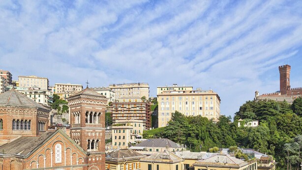 A cityscape with historic buildings, a prominent tower, and a sign indicating 'SMART WORKING'. - Castello d'Albertis by Wonderful Italy (Genova)