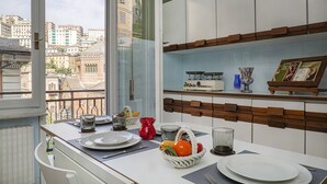 A modern kitchen with white cabinets, a wooden shelf, and a view of the cityscape. - Castello d'Albertis by Wonderful Italy (Genova)