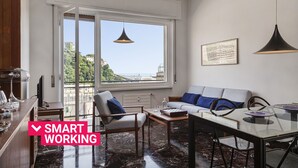 A modern living room with a sofa, coffee table, and dining table. A large window offers a view of a cityscape. - Castello d'Albertis by Wonderful Italy (Genova)