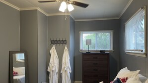 Un dormitorio con cama, cómoda, espejo y ventilador de techo.