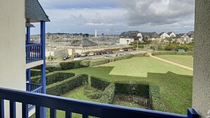 Blick vom Balkon auf einen Hafen mit Booten, einen Parkplatz und Wohnhäuser.